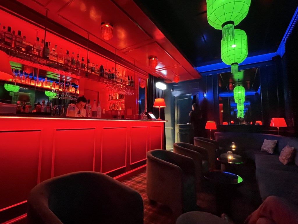 A long bar room with red, green and blue colored lights.